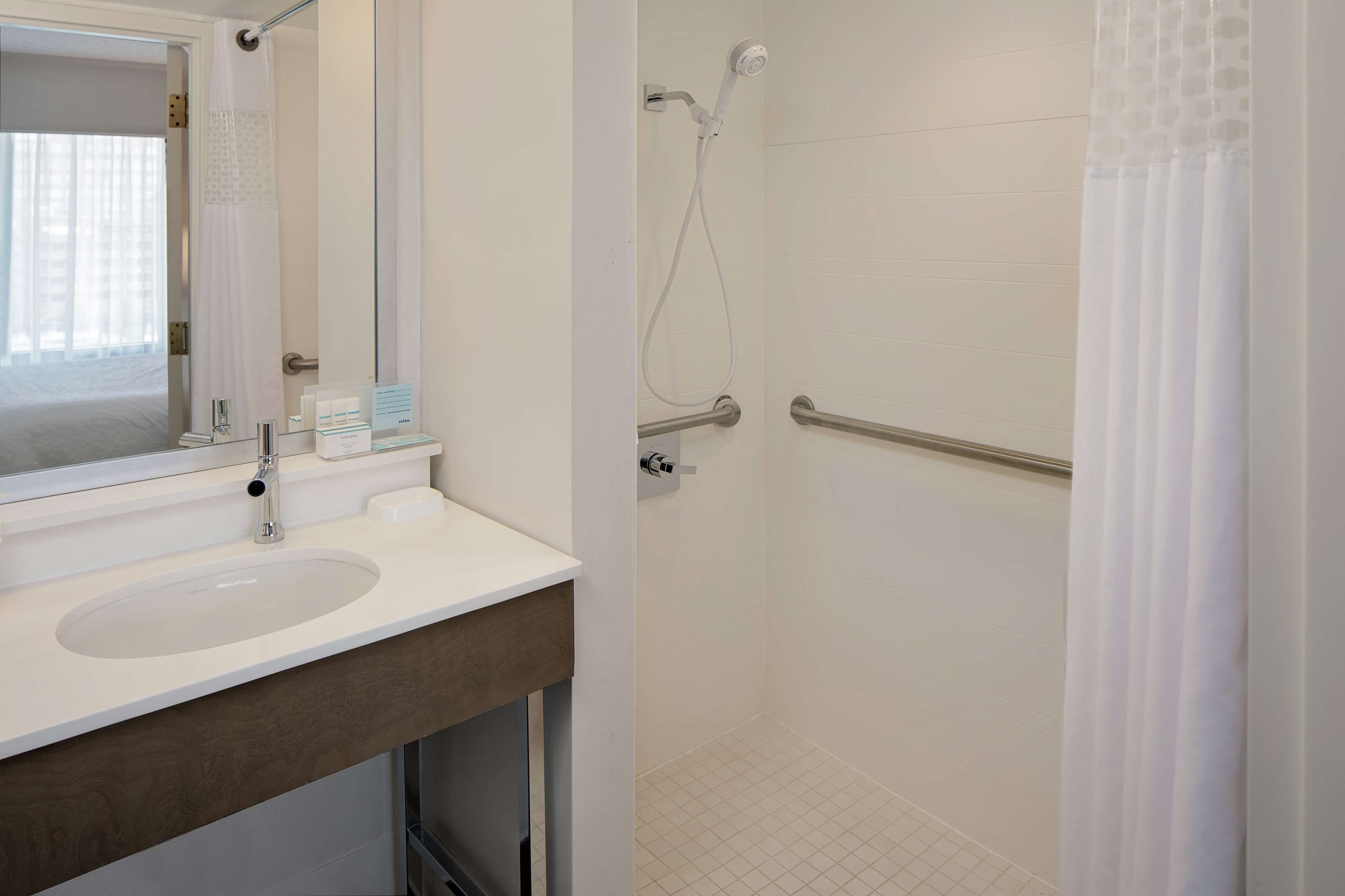 Un bagno con lavandino, specchio, doccia e porta in vetro.