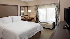 A hotel room with a large bed, a desk with a flat-screen TV, a desk lamp, and a window with curtains. - Hampton Inn Louisville Downtown (Louisville)