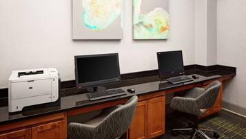 A workspace with two monitors, a printer, and two patterned chairs.
