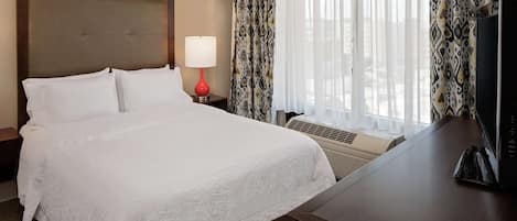 Una habitación de hotel con una cama grande, un escritorio, una lámpara y un televisor.