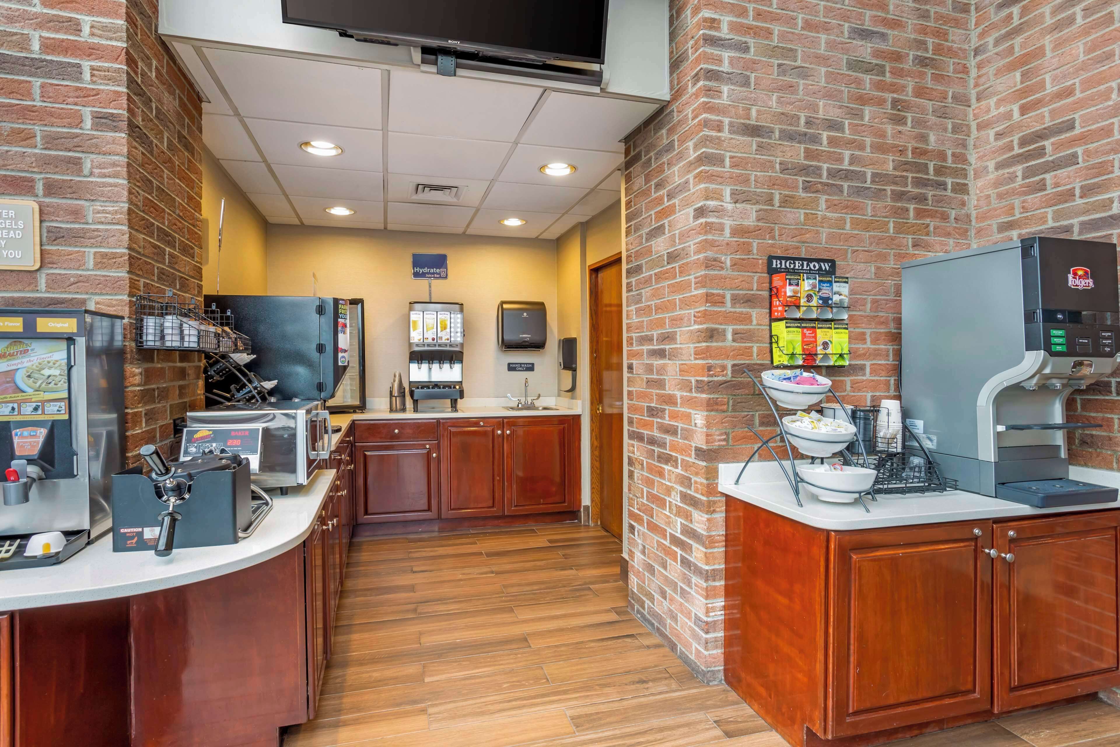 Una cocina de hotel con una máquina de café, un dispensador de bebidas y una zona de bufé con alimentos.