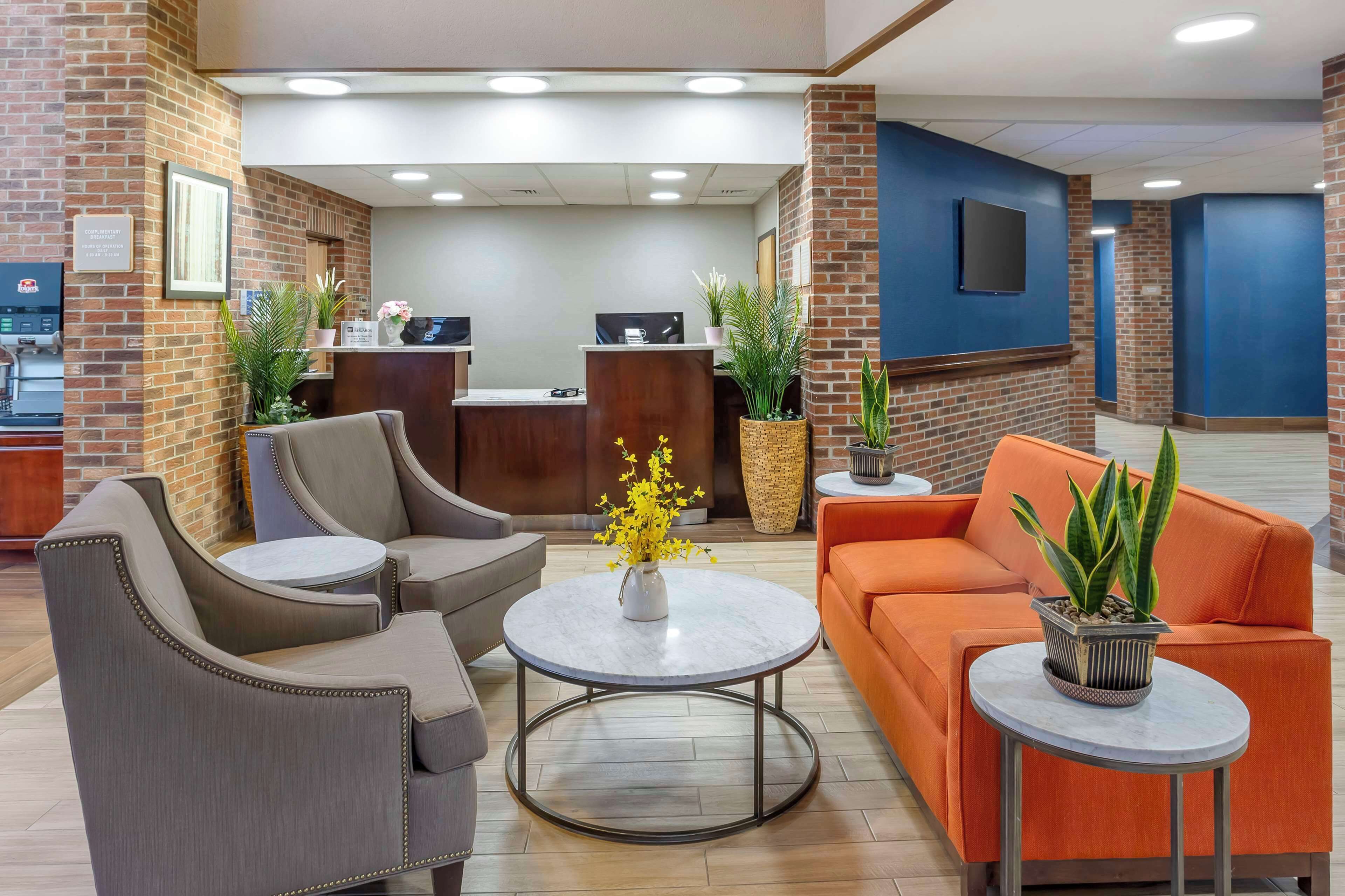 A lobby with a reception desk, seating area, and potted plants.