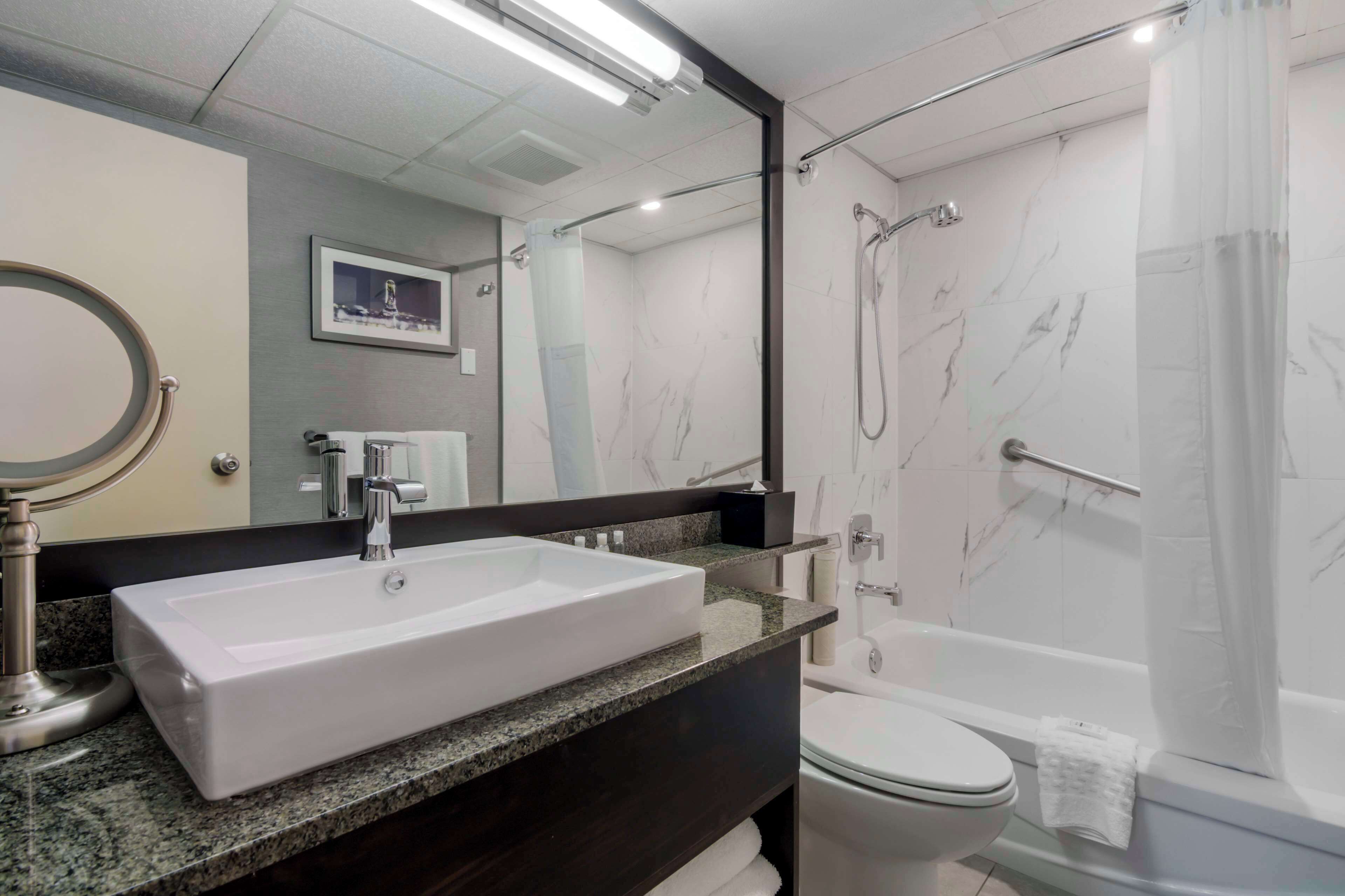 A modern bathroom with a large rectangular sink, a toilet, and a walk-in shower.
