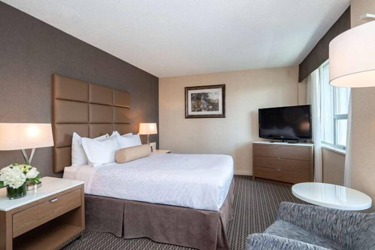 Ein Hotelzimmer mit Bett, Fernseher, Schreibtisch und Stuhl.