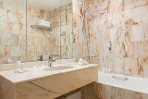 Bathroom features a bathtub with handheld showerhead and faucet, along with a marble vanity and large mirror.