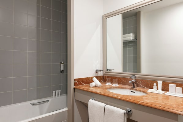 Modern bathroom with a large mirror, sink, and shower area, offering a clean and functional space.
