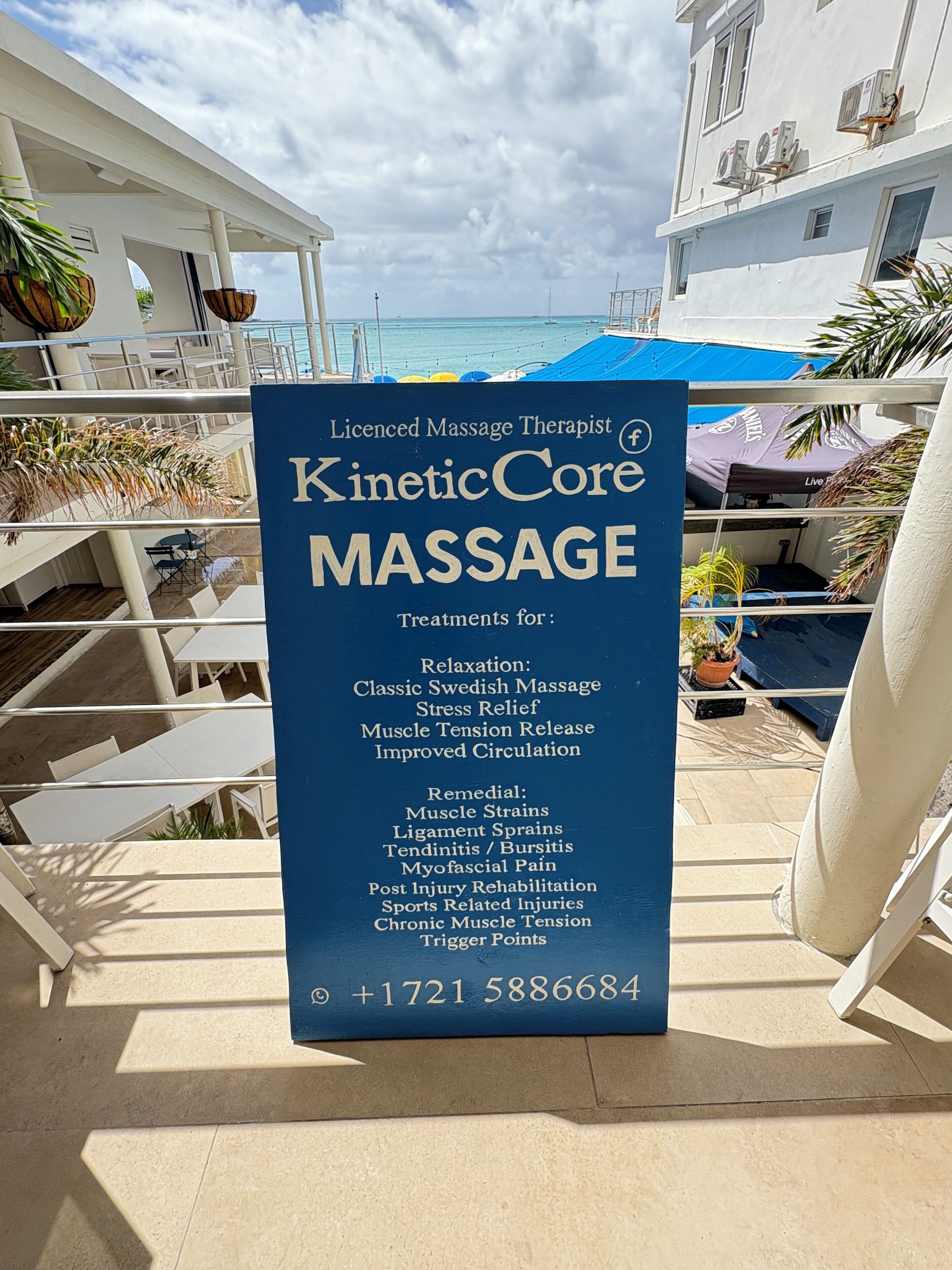 Señal de terapia de masajes para KineticCore Massage, con una lista de tratamientos y un número de teléfono.