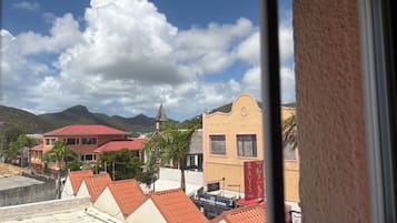Une vue de bâtiments aux toits rouges et d’une église dotée d’un clocher, sous un ciel partiellement nuageux.