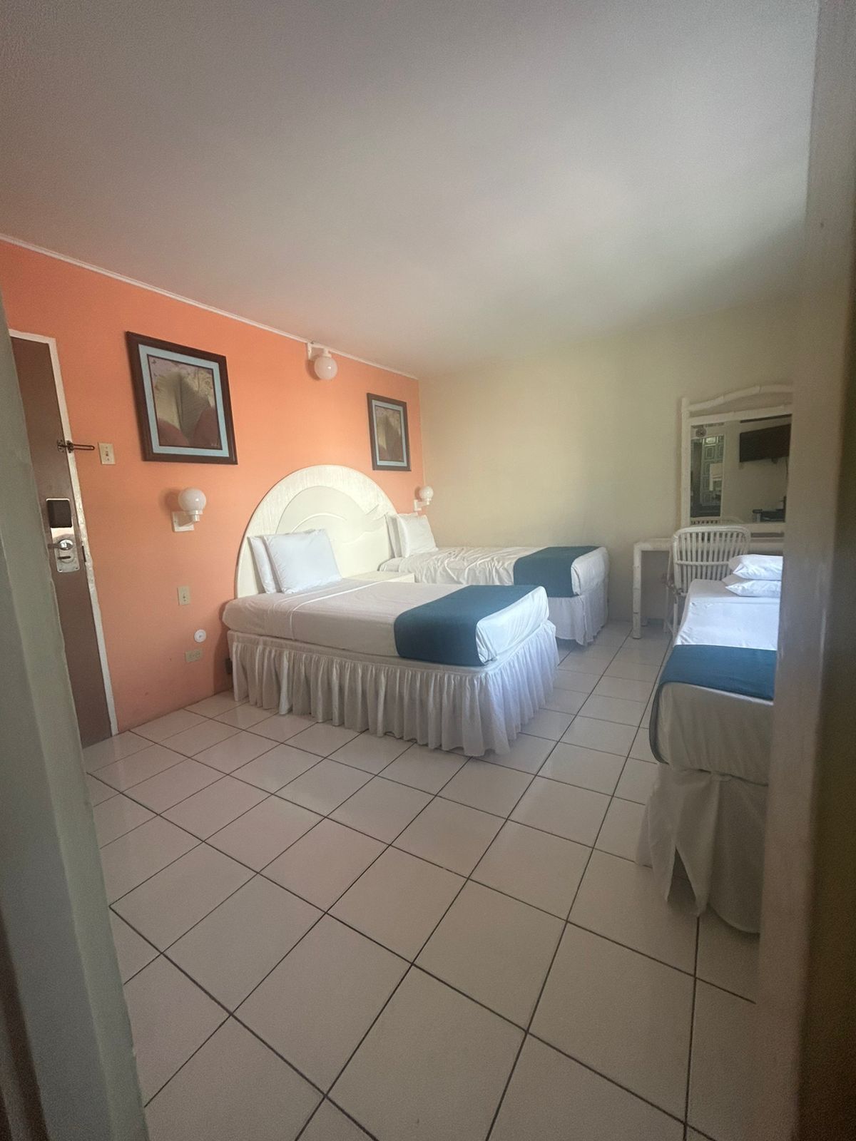 A hotel room with two beds, a large window, and a door leading to a bathroom.