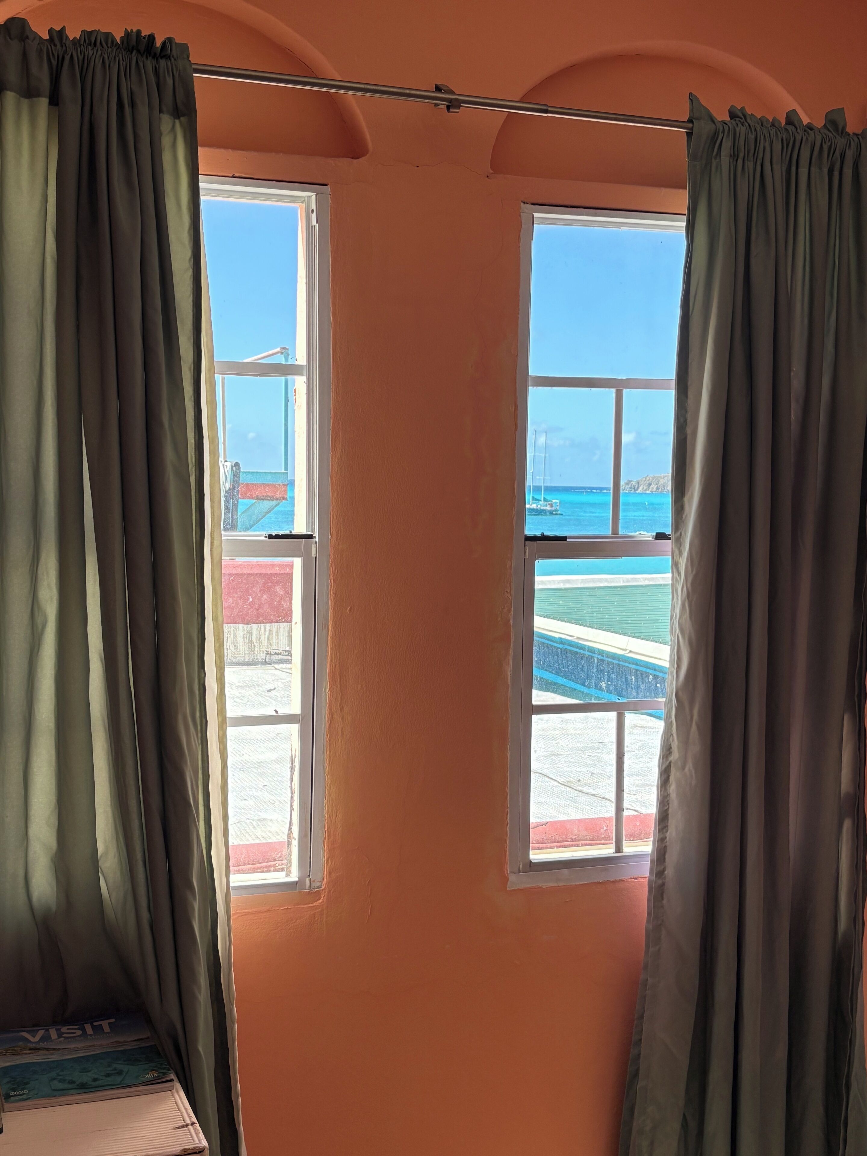 Una habitación con dos ventanas, cada una con vistas al mar y a la costa distante.