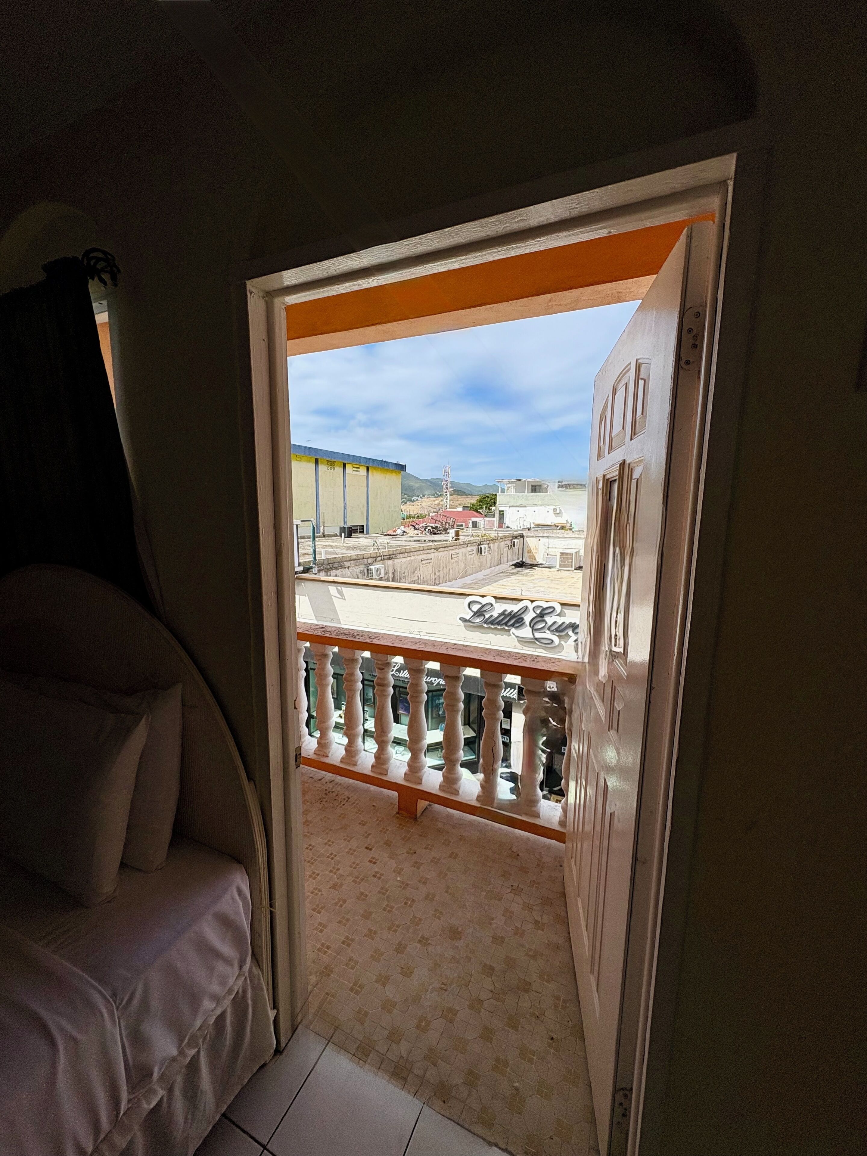 A room with a balcony, a sofa, and a view of the outside.