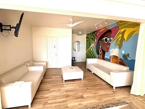 A modern living room with two white sofas, a coffee table, and a ceiling fan.