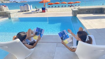 Una piscina al aire libre, camas de piscina con cargo, sombrillas