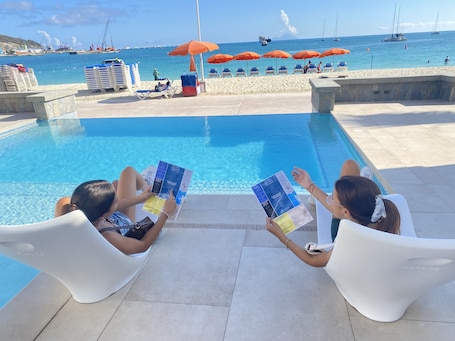 Una piscina al aire libre, camas de piscina con cargo, sombrillas