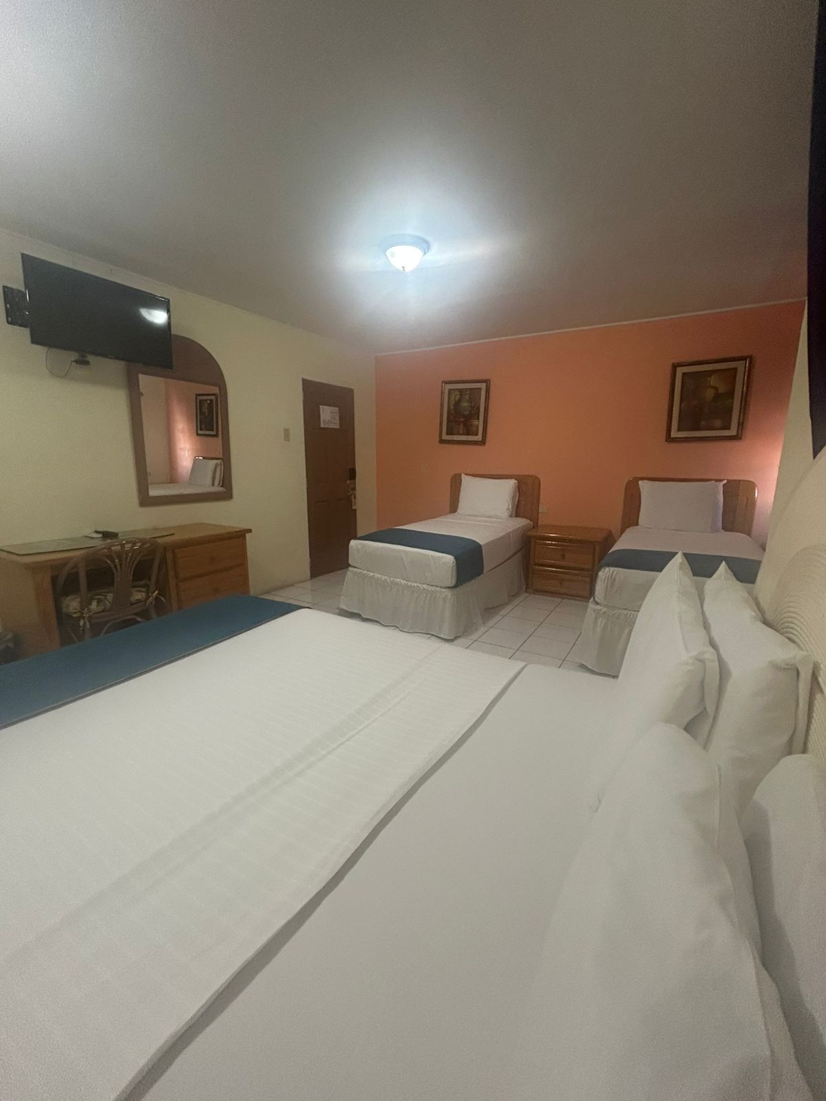 A hotel room with two single beds, a desk, and a chair.