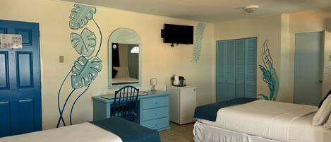 A bedroom with two beds, a desk, a chair, a dresser, a television, and a wardrobe.