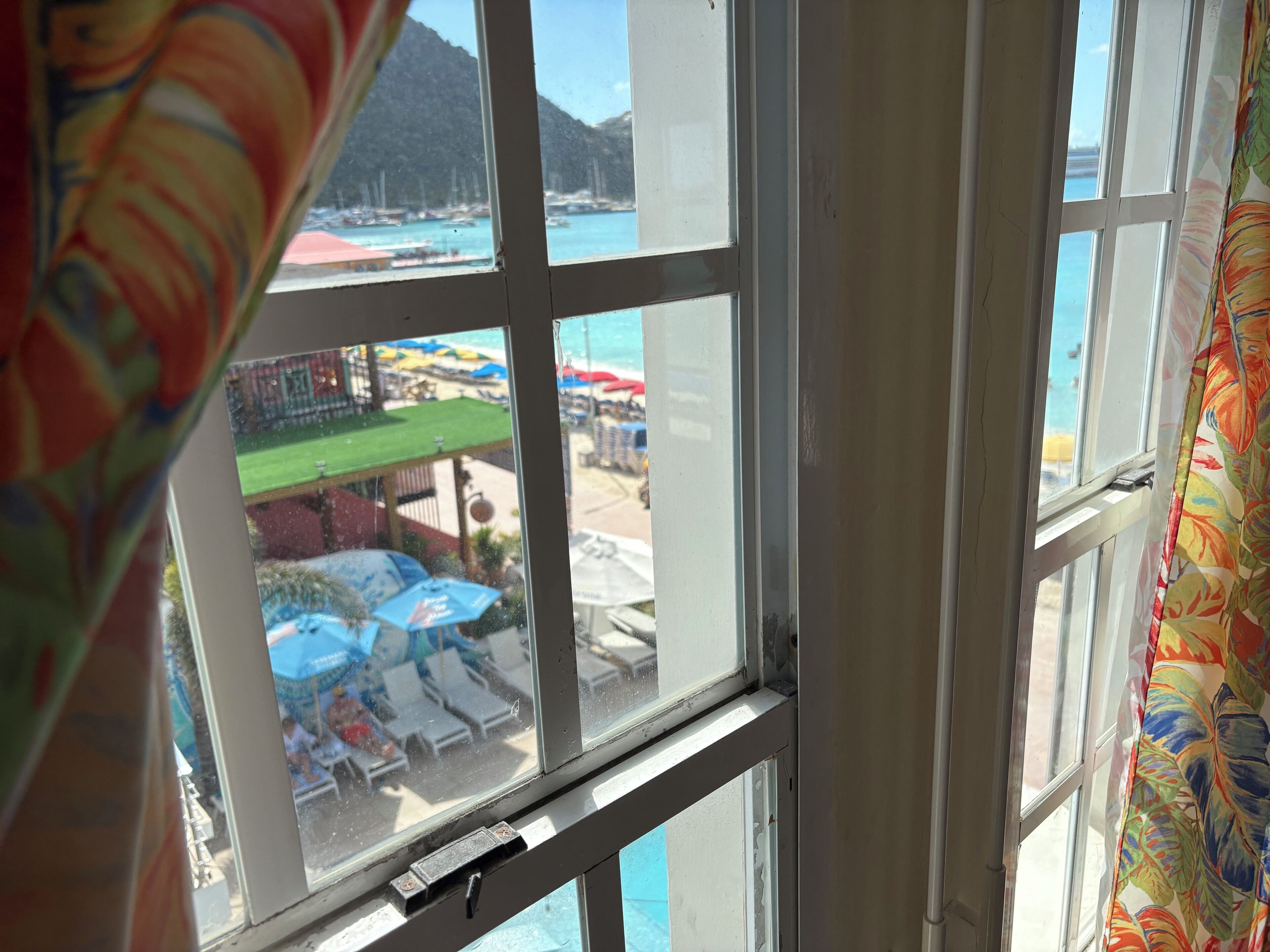 A view through a window with a view of a beach and a mountain in the background.