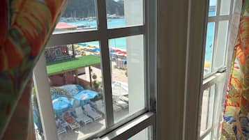 A view through a window with a view of a beach and a mountain in the background.