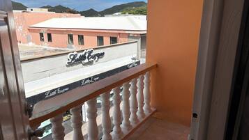 A balcony with a view of a building named 'Little Curve' and a mountainous landscape in the background.