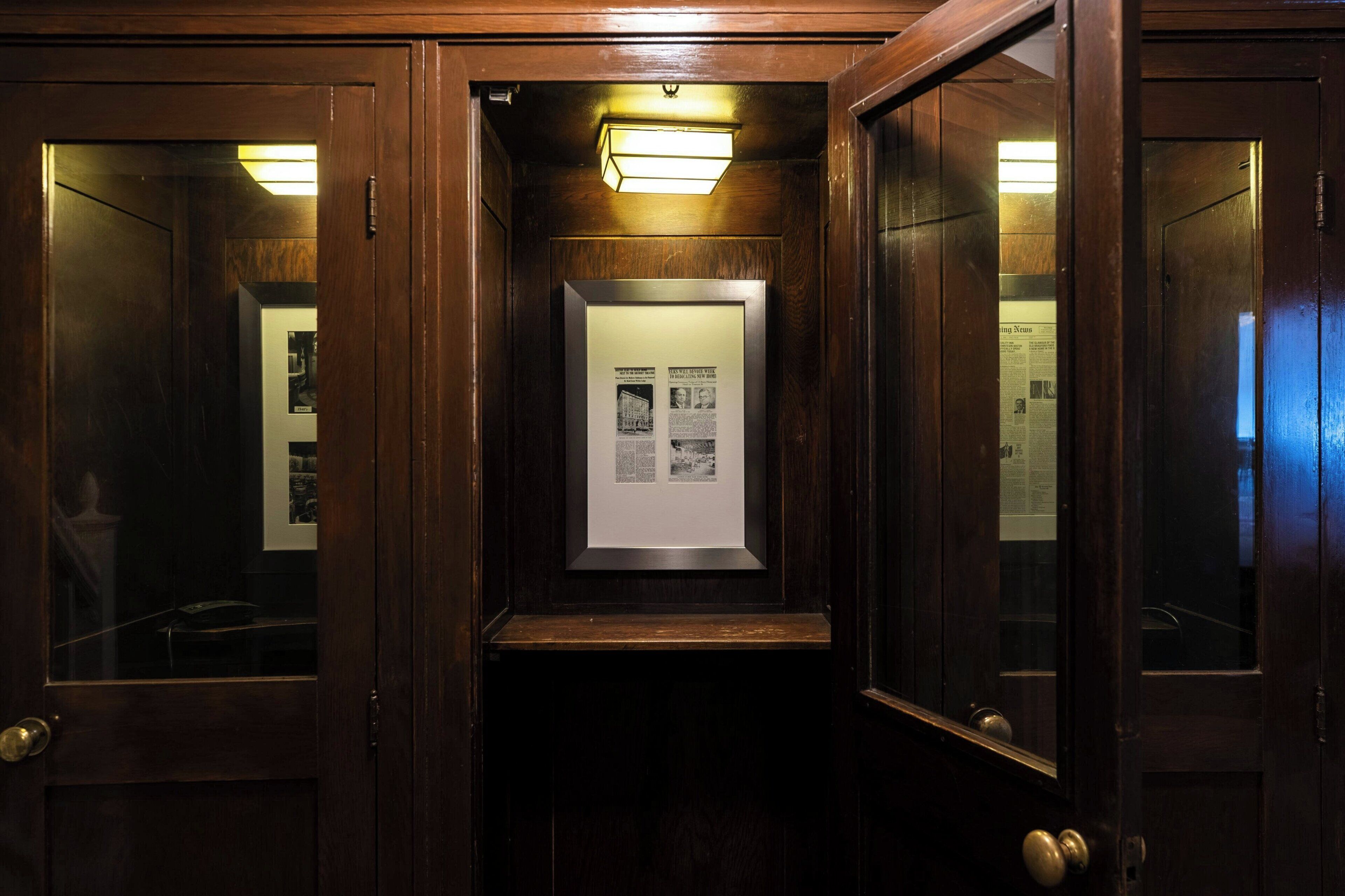 Un ascensor amb portes de fusta i una fotografia d'un edifici emmarcada a la paret.