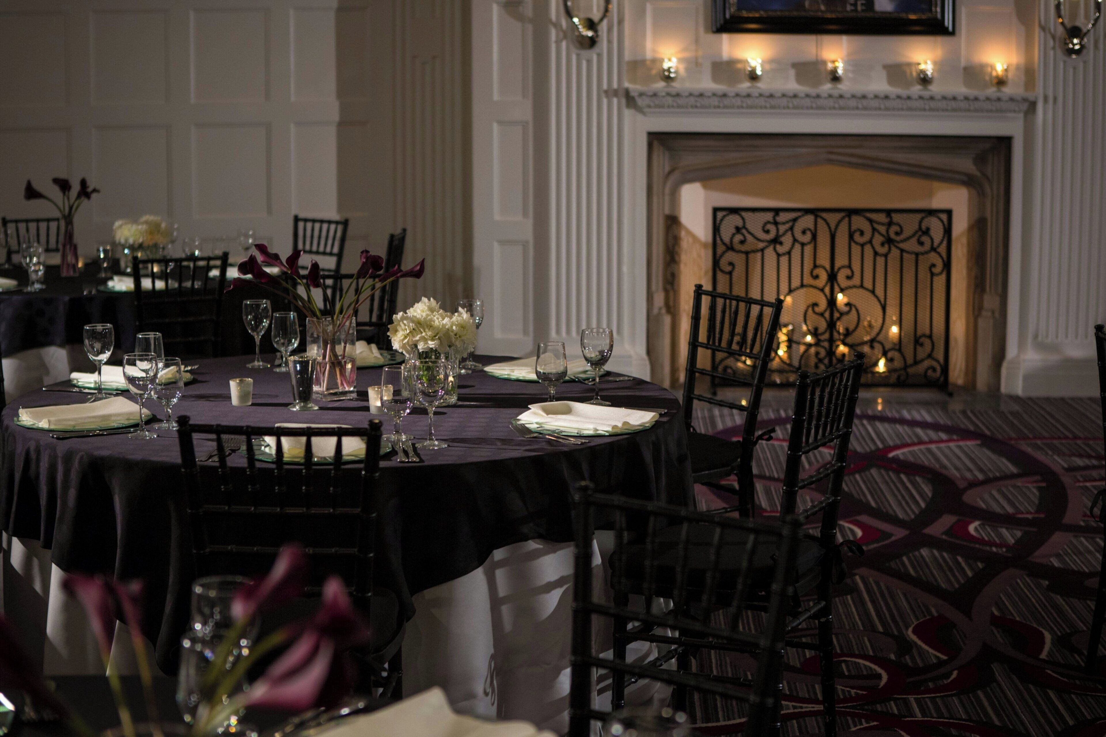 A formal dining room with a fireplace, elegant table settings, and classic decor.