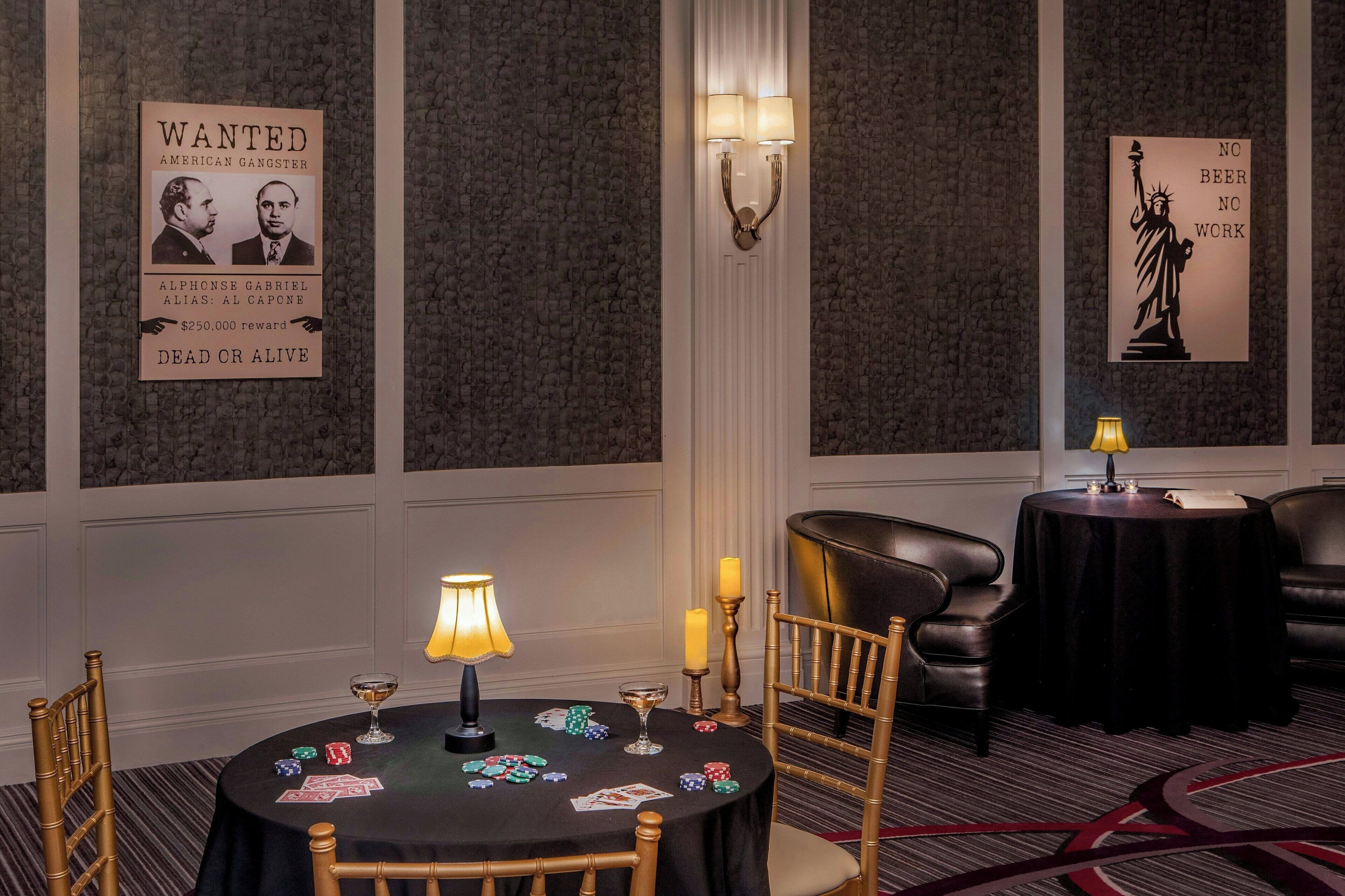 A hotel room with a poker table, a lamp, candles, and a poster of the Statue of Liberty.