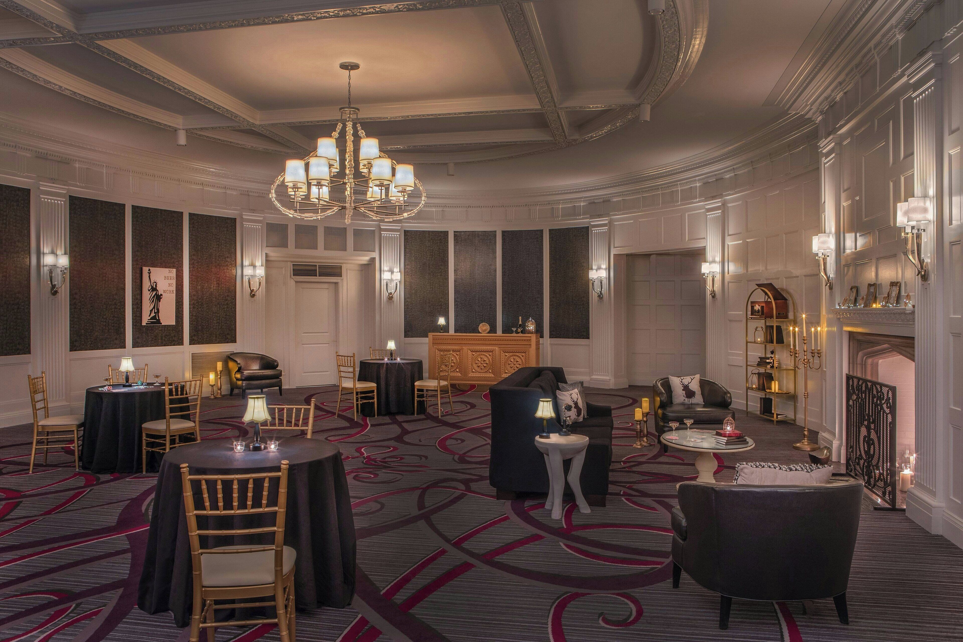 A luxurious hotel lobby with a grand chandelier, elegant furniture, and a patterned carpet.