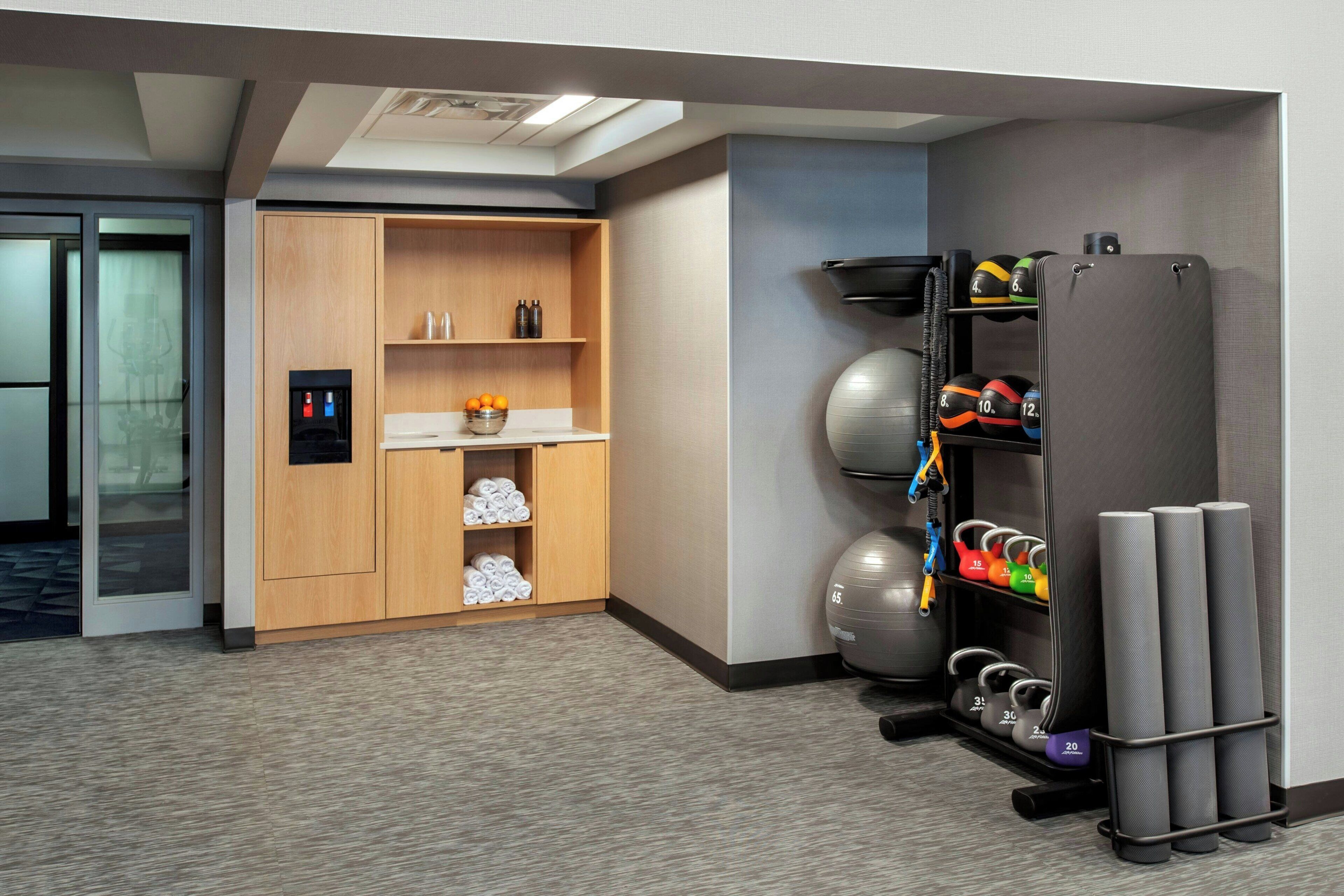 Habitación de hotel con zona de gimnasio que incluye equipo de ejercicio y un minibar.
