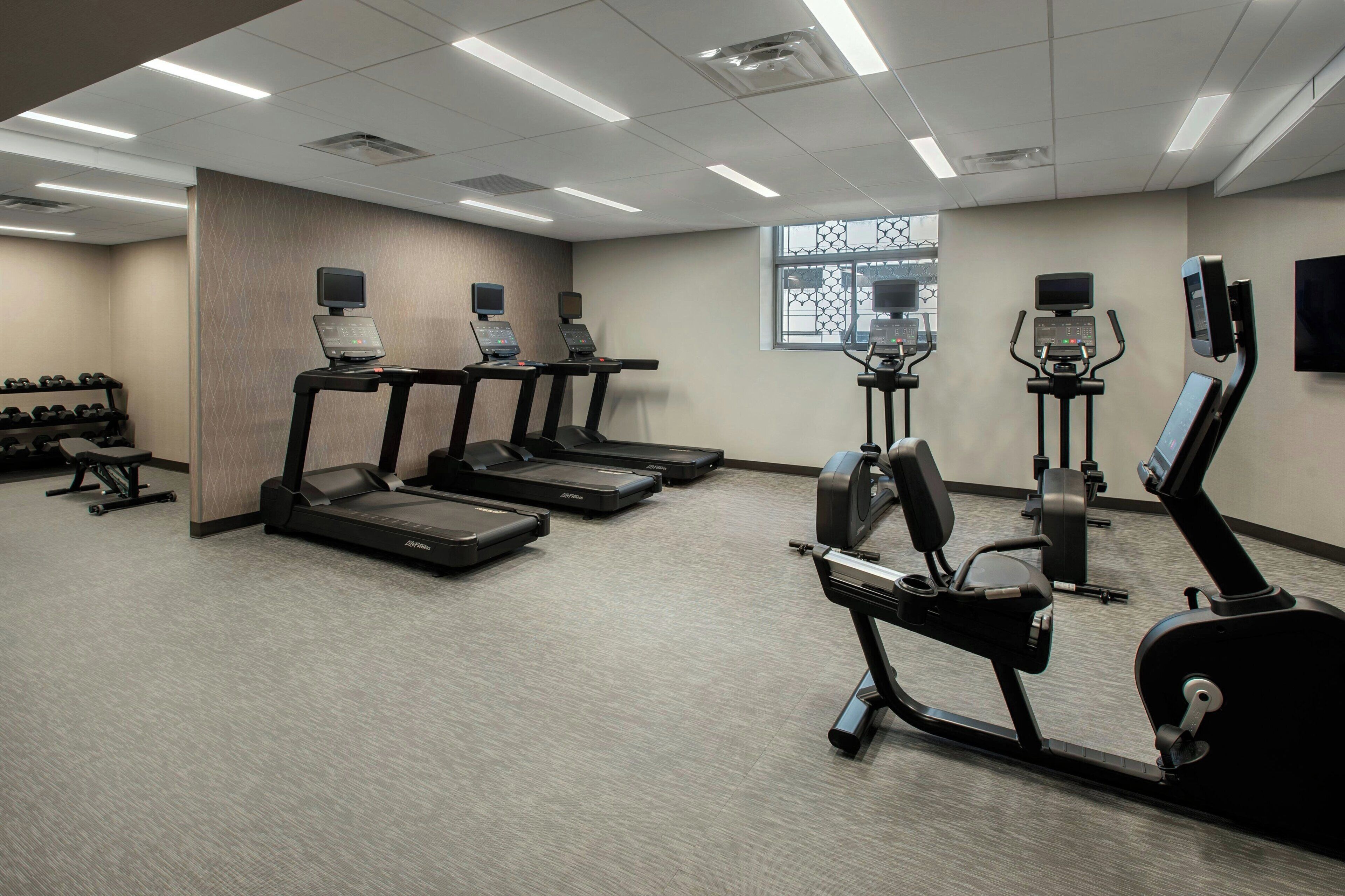 Un gimnasio equipado con cintas de correr, elípticas y un rack de pesas.