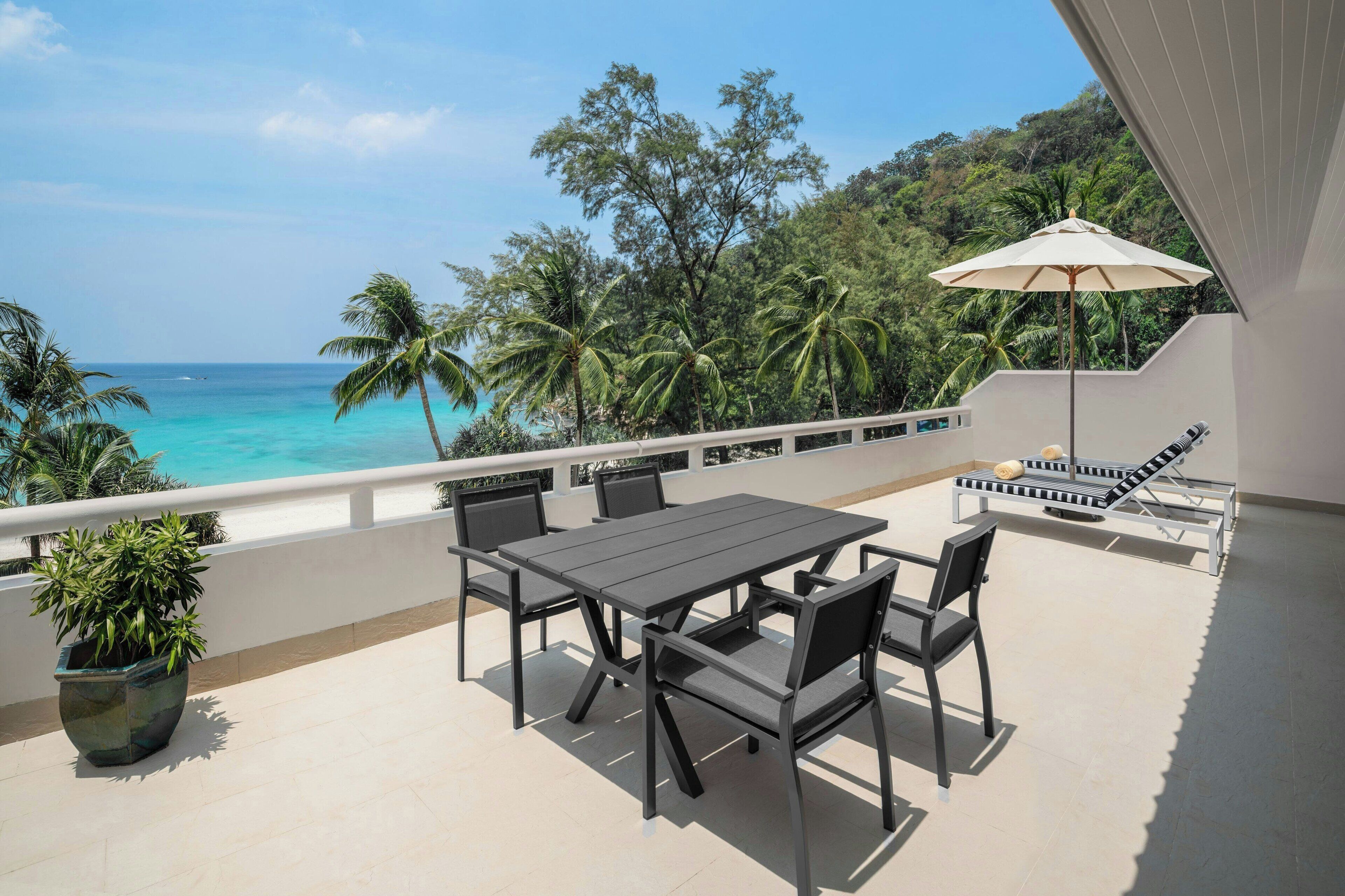 A balcony with a table and chairs, a potted plant, and a lounge chair with an umbrella.