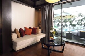 A modern living room with a sofa, a glass coffee table, and a view of a pool area.