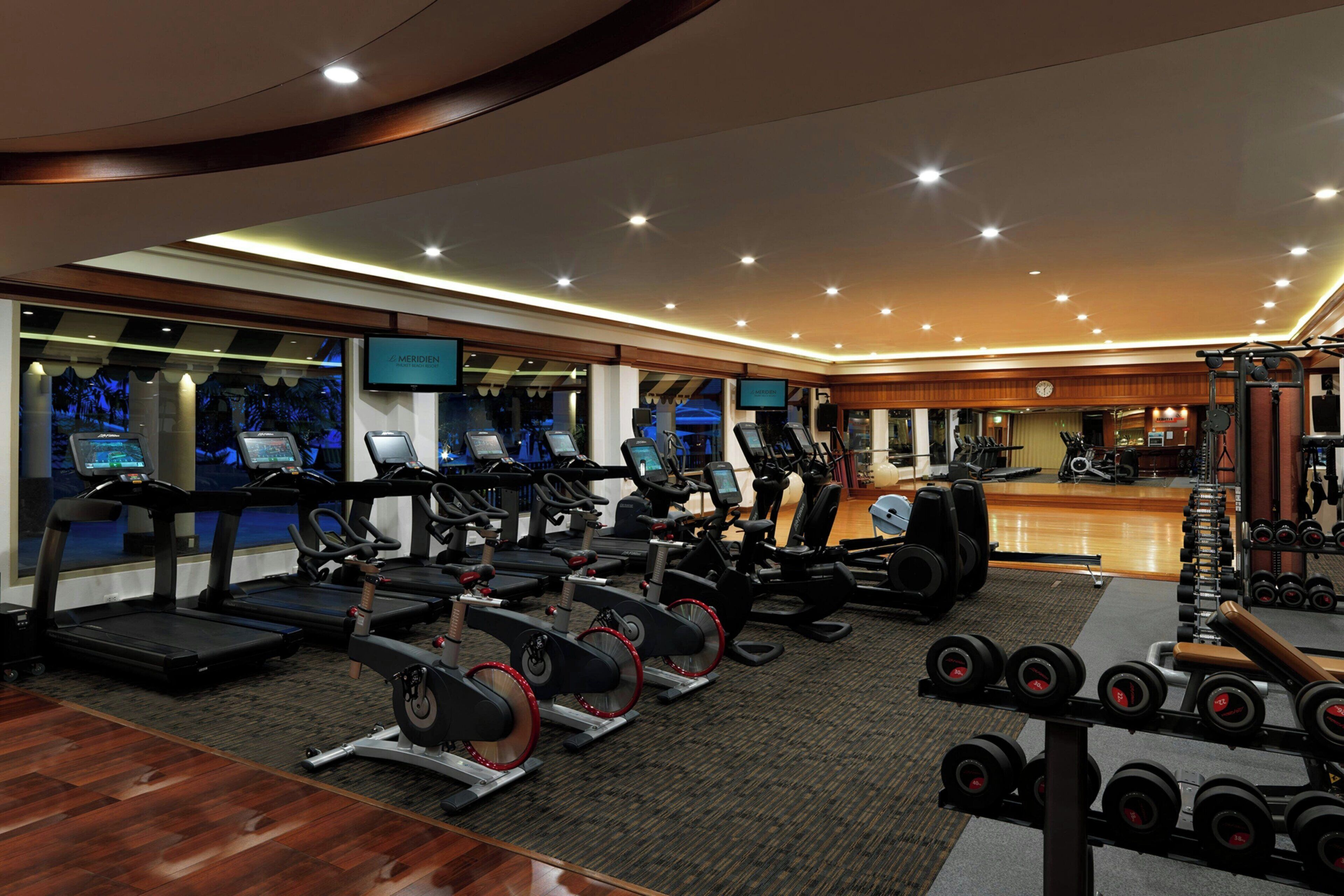 Un gimnasio moderno con cintas de correr, elípticas y pesas libres.
