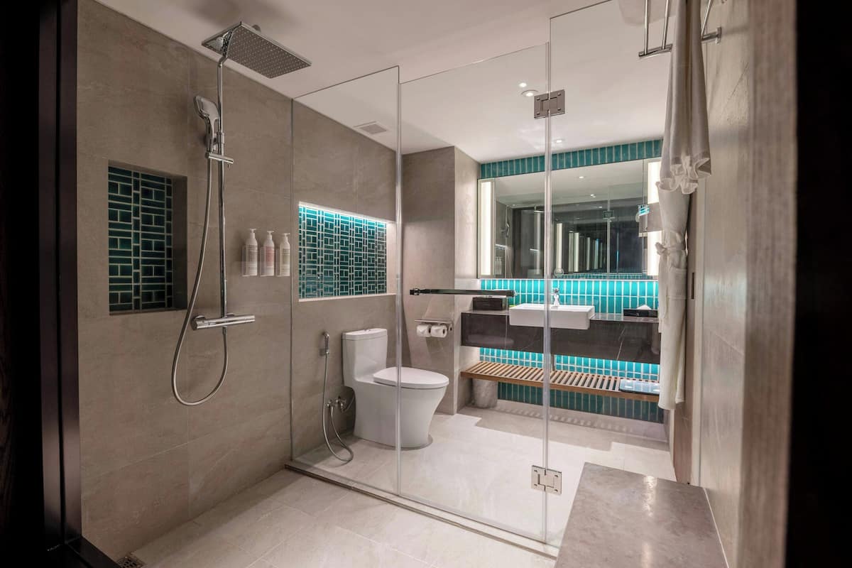 A modern bathroom with a glass-enclosed shower, a toilet, and a sink.