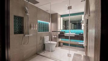 A modern bathroom with a glass-enclosed shower, a toilet, and a sink.