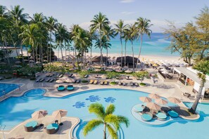 Relax by the resort's turtle-shaped pool, surrounded by lounge chairs and umbrellas, with the ocean view in the background.
