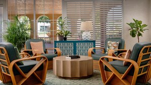 A room with wicker furniture, a round coffee table, and potted plants.