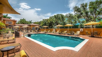 Una piscina al aire libre, sombrillas, sillones reclinables de piscina
