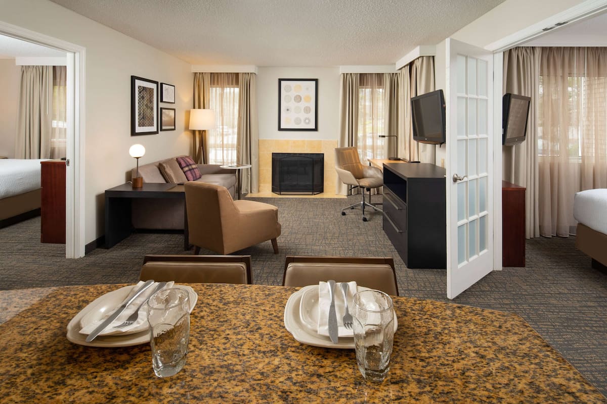 Une chambre d’hôtel comprenant un coin repas, un canapé, une cheminée et un téléviseur.
