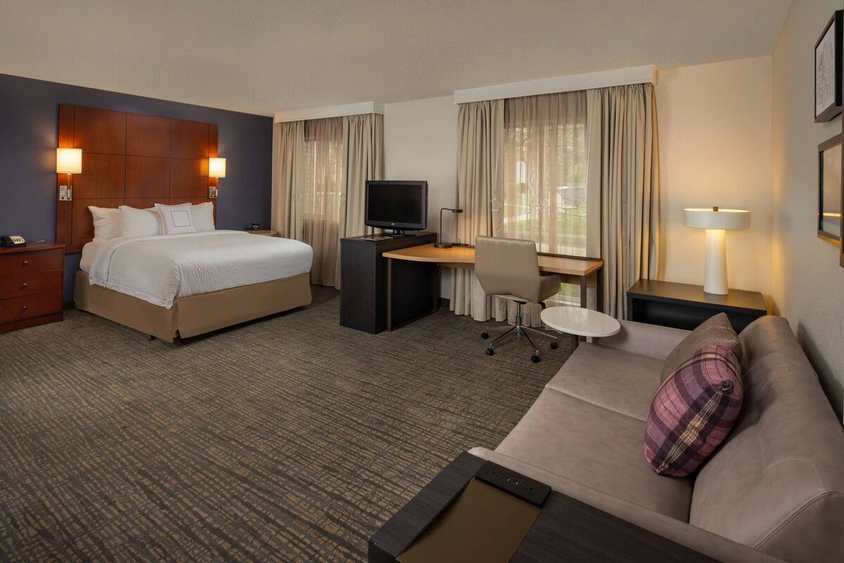Une chambre d’hôtel avec un lit, un bureau, une chaise et un canapé.