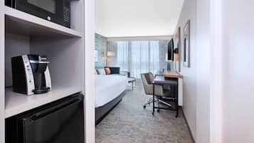 Een hotelkamer met een bed, bureau, stoel en kitchenette.