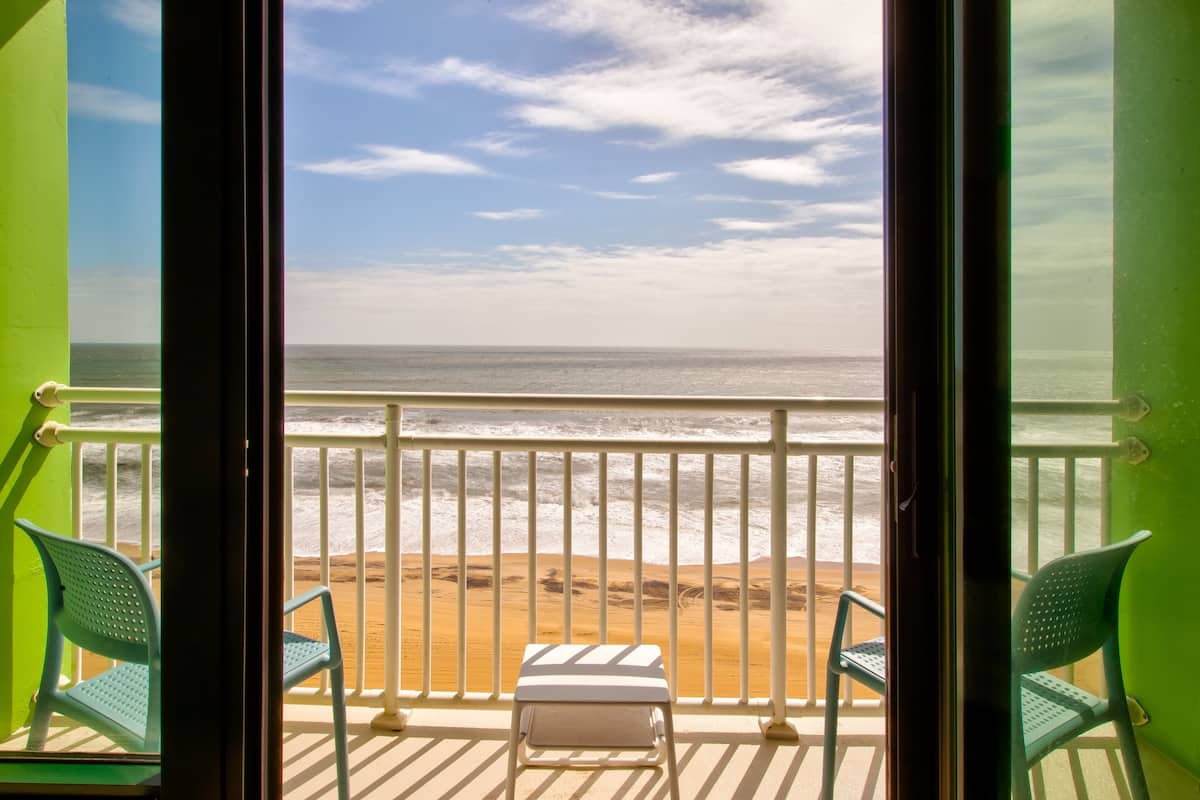 A balcony with a view of the beach and ocean.