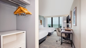 Quarto de hotel com cama, escrivaninha, cadeira e armário.