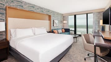 A hotel room with a large bed, a sofa, a desk, and a TV.