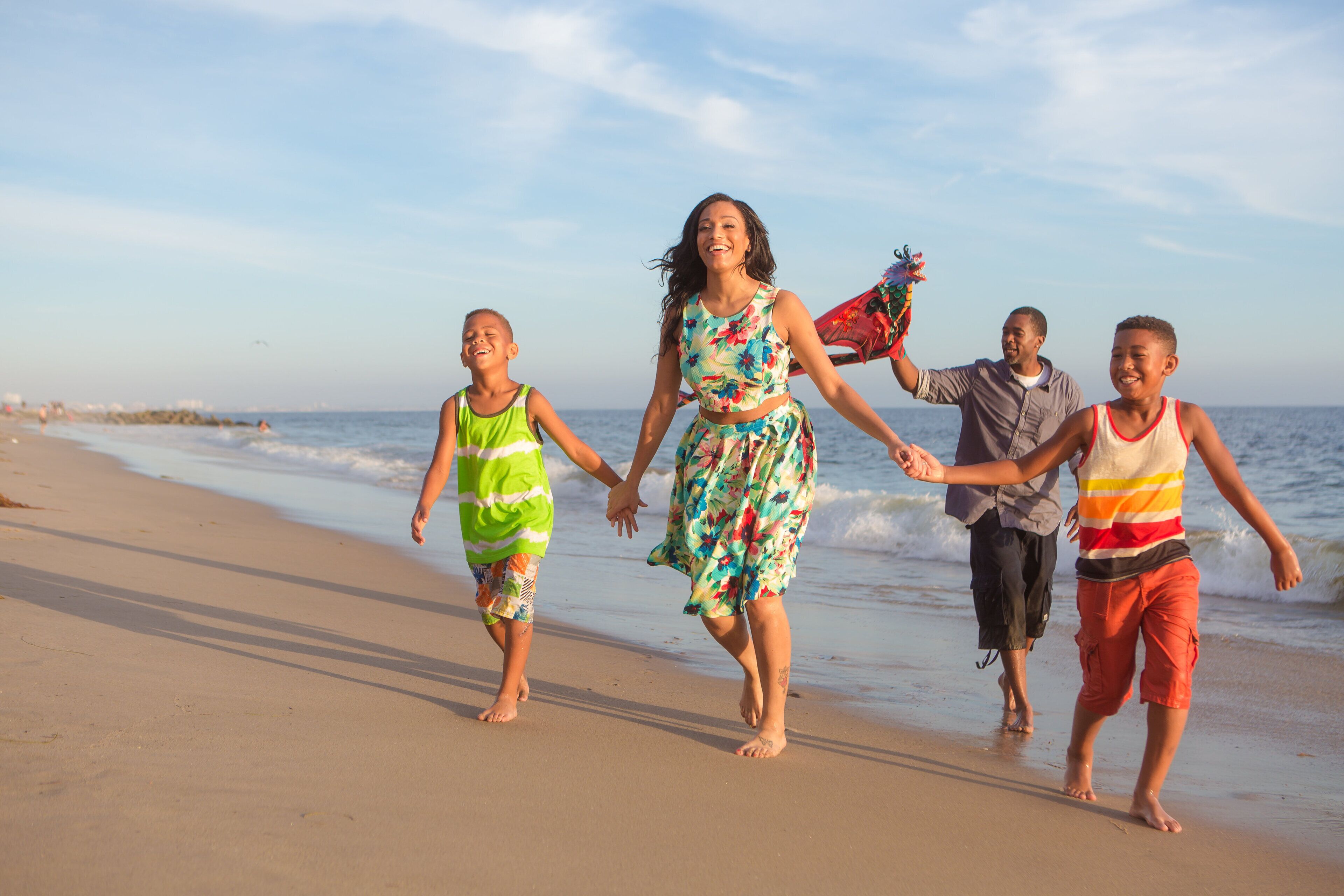 A family walking on a sandy beach with the ocean in the background.