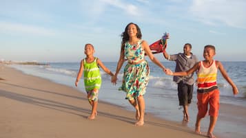 Une famille se promène sur une plage de sable, avec l’océan en arrière-plan.