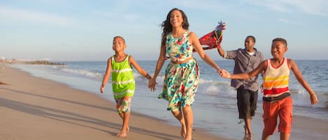 Une famille se promène sur une plage de sable, avec l’océan en arrière-plan.
