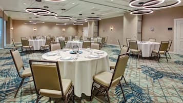 A conference room with round tables, chairs, and modern lighting fixtures.