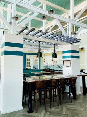 A restaurant with a high ceiling, exposed beams, and a central island with seating.