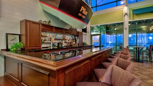 Uma área de bar com balcão de madeira, banquetas e um letreiro grande com a inscrição "Pillar Key West".