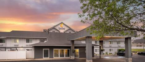 A hotel with a sign for 'Comfort Inn & Suites' and a covered parking area.
